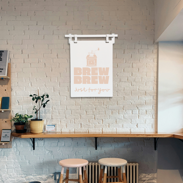 Room interior with a 'Brew Brew' sign on a white brick wall, wooden shelf, and stools.