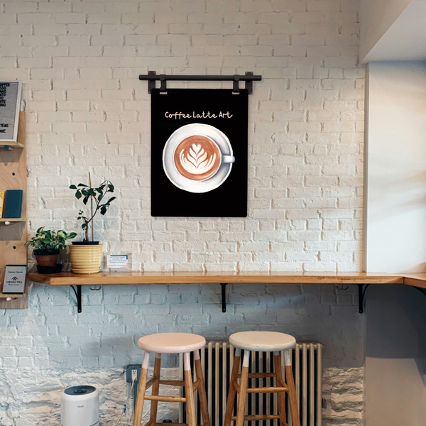 Coffee latte art poster on a wall in a cafe setting with stools and plants.