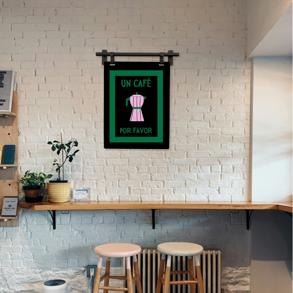 Coffee Art Framed artwork on a white brick wall above a wooden shelf with plants and bar stools.
