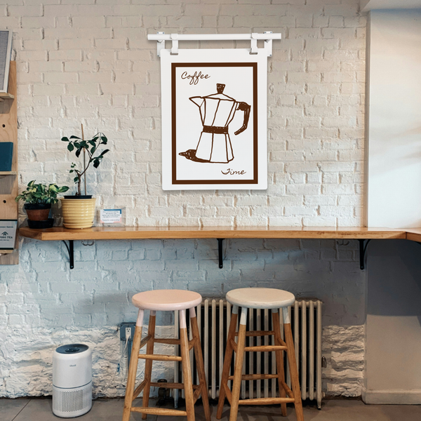 Coffee-themed wall art above a wooden counter with stools in a cozy cafe setting.