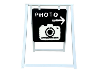 White metal sidewalk business sign displaying photo with a arrow in a white boardground
