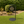 Black metal pathway sign with a circular sign on grass and shrubs in the background
