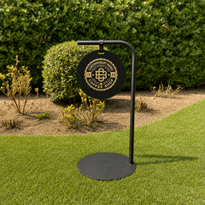 Black metal pathway sign with a circular sign on grass and shrubs in the background