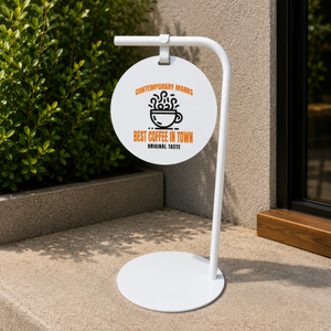 Outdoor pathway sign with 'Best Coffee in Town' text on a white stand.