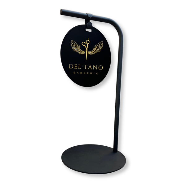 Modern shop sign with round metal board featuring 'Del Tano Barberia' logo on a white background