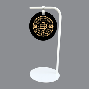 Black and gold coffee shop logo on a white retail standing sign against a gray background