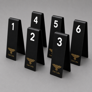 Set of black table number stands with numbers 1 to 6 and 'Owl Cafe' logo on a gray background