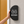 A black half round restroom projection sign with white male and female restroom icons and the word RESTROOM, mounted on a light gray wall next to a mustard yellow door.