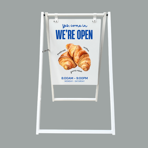 Outdoor sign indicating a bakery is open with a croissant illustration on a gray background