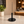 A minimalist black oval tabletop display in a perfect sideview on a light stone countertop in a softly blurred cafe setting.