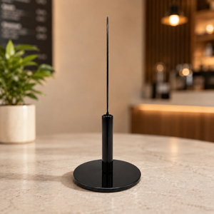A minimalist black oval tabletop display in a perfect sideview on a light stone countertop in a softly blurred cafe setting.