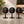 Three round black tabletop signs on a countertop in a cafe setting. Each sign displays custom logo in white script with a large orange number underneath: 01, 02, and 03.