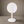 A modern white round tabletop stand with round base, set against a neutral brown studio background.