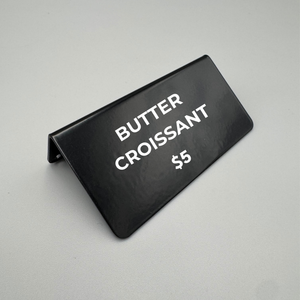 Black bakery sign with 'Butter Croissant $5' text on a gray background