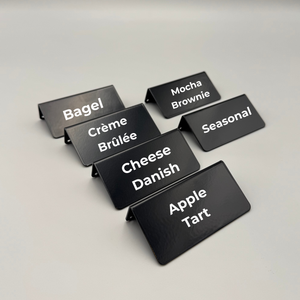 Black pastry menu signs with white text on a light gray background