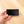 Hand holding a black rectangular counter display sign on a wooden surface
