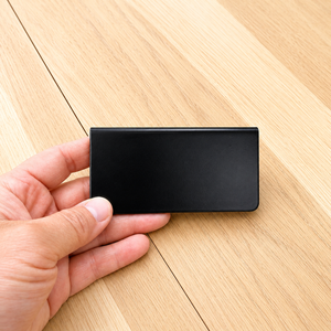 Hand holding a black rectangular counter display sign on a wooden surface