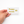 Hand holding a counter sign dispaly with 'Poppy Seeds $5' text on a white background