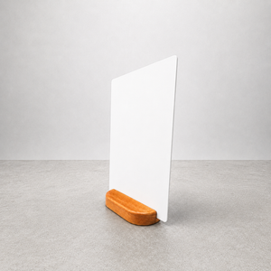 A minimalist white tabletop sign holder featuring a vertical white board sitting on a rounded rectangular wooden base.