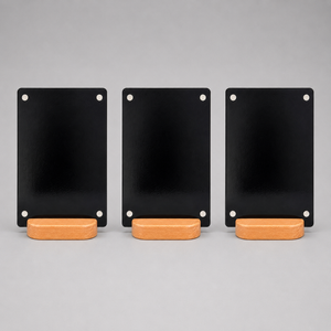 Three black rectangular metal display boards with silver magnets, each resting on a light wood stand, arranged side by side.  