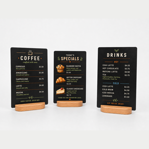 Three black cafe shop menu signs on solid wooden stands. The left one is for coffee, the middle for today's specials, and the right for drinks.