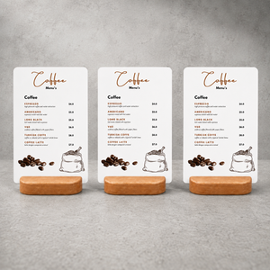 Three printed table coffee menu signs with coffee illustrations are displayed on small wooden stand