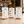 Three vertical printed table menu coffee menu signs on small wooden stands, displayed on a countertop in a cafe interior. The magnetic menu show coffee items, dessert specials, and hot/cold drinks with prices.