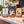 Three coffee-themed counter sign on wooden stands displayed on a cafe counter. The signs feature designs for a coffee club, morning coffee specials, and weekend coffee deals, with a blurred coffee shop interior in the background.