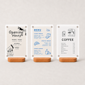 Three white minimalist paper cafe menu against magnetic table menu signs.  The left card reads 'Opening Hours' with black line drawings; the middle card shows a 'MENU' with blue line drawings; the right card lists 'COFFEE' items with black line drawings.