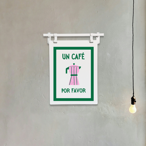 Sign on a wall with text 'UN CAFé POR FAVOR' and a pink figure, hanging below a light bulb.